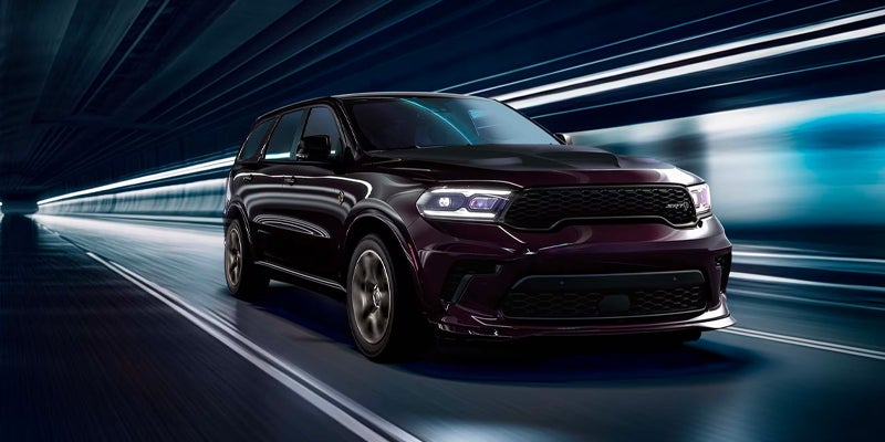 A dark-colored performance SUV is driving through what appears to be a tunnel or a digitally enhanced high-speed roadway scene