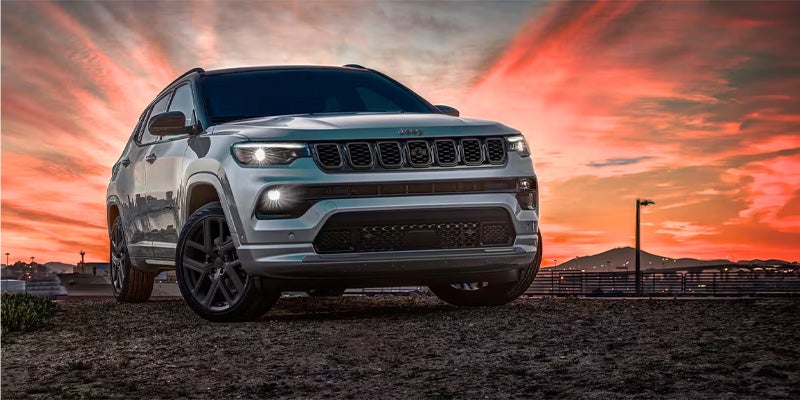 Modern white SUV photographed from a low front-left angle during sunset