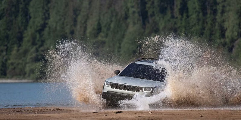 Jeep SUV splashing through water during off-road driving adventure