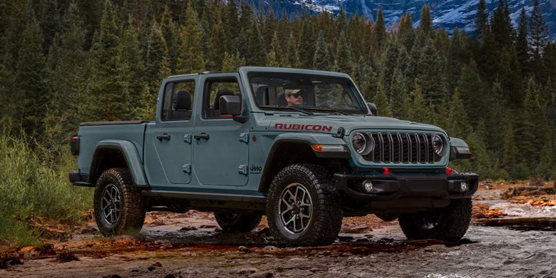 Light blue Jeep Gladiator Rubicon pickup truck parked on a rugged outdoor trail