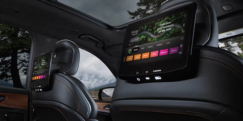 Rear-seat entertainment screens inside a Jeep SUV with panoramic sunroof