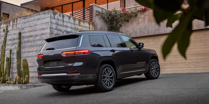 Rear three-quarter view of a black Jeep Grand Cherokee SUV parked in a residential area