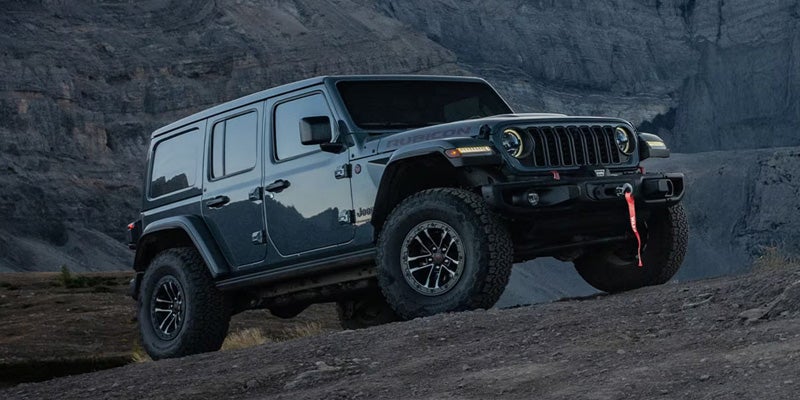 Black Jeep Wrangler climbing rocky terrain during an off-road adventure