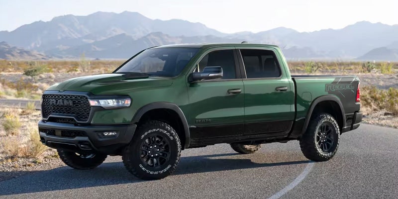 Green Ram pickup truck parked on a road with mountain scenery in the background