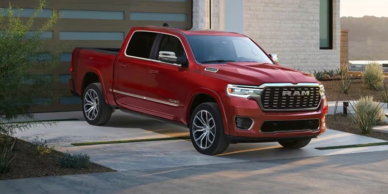 A new red Ram 1500 pickup truck parked outside a modern house with a garage door